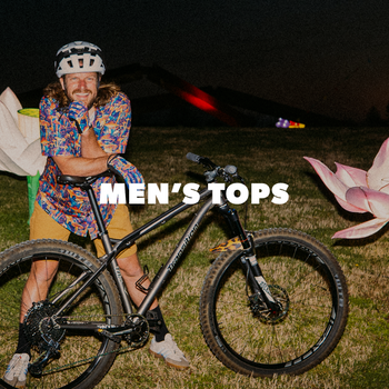 Person on a bike with colorful flower-shaped lanterns at night, featuring 'Men's Tops' text.