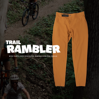 Orange pants displayed with 'Trail Rambler' branding in a forest setting.