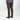 A person shown from the back wearing dark brown slim-fit pants, a patterned blue shirt, and black low-top sneakers against a light gray studio background.