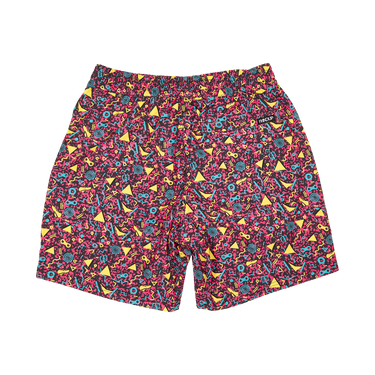 A pair of men's swim trunks featuring a vibrant, dense abstract pattern of pink, yellow, teal, and black shapes, photographed flat against a solid white background.
