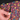Close-up of a person's hand pulling a black zipper on colorful patterned shorts. The shorts feature a black background with a vibrant pink, yellow, and blue geometric and mechanical design.