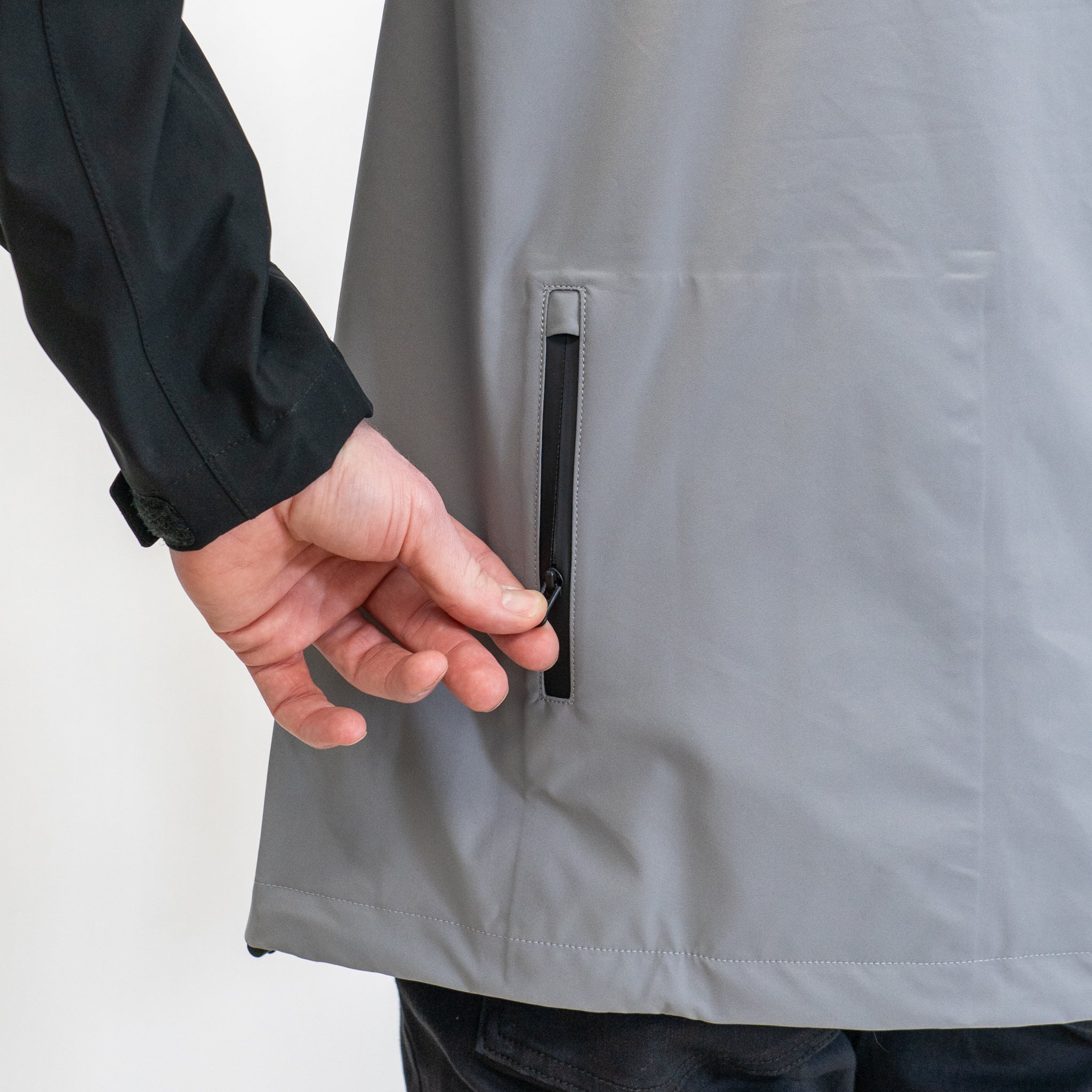 a person unzipping the back pocket of a grey and black jacket