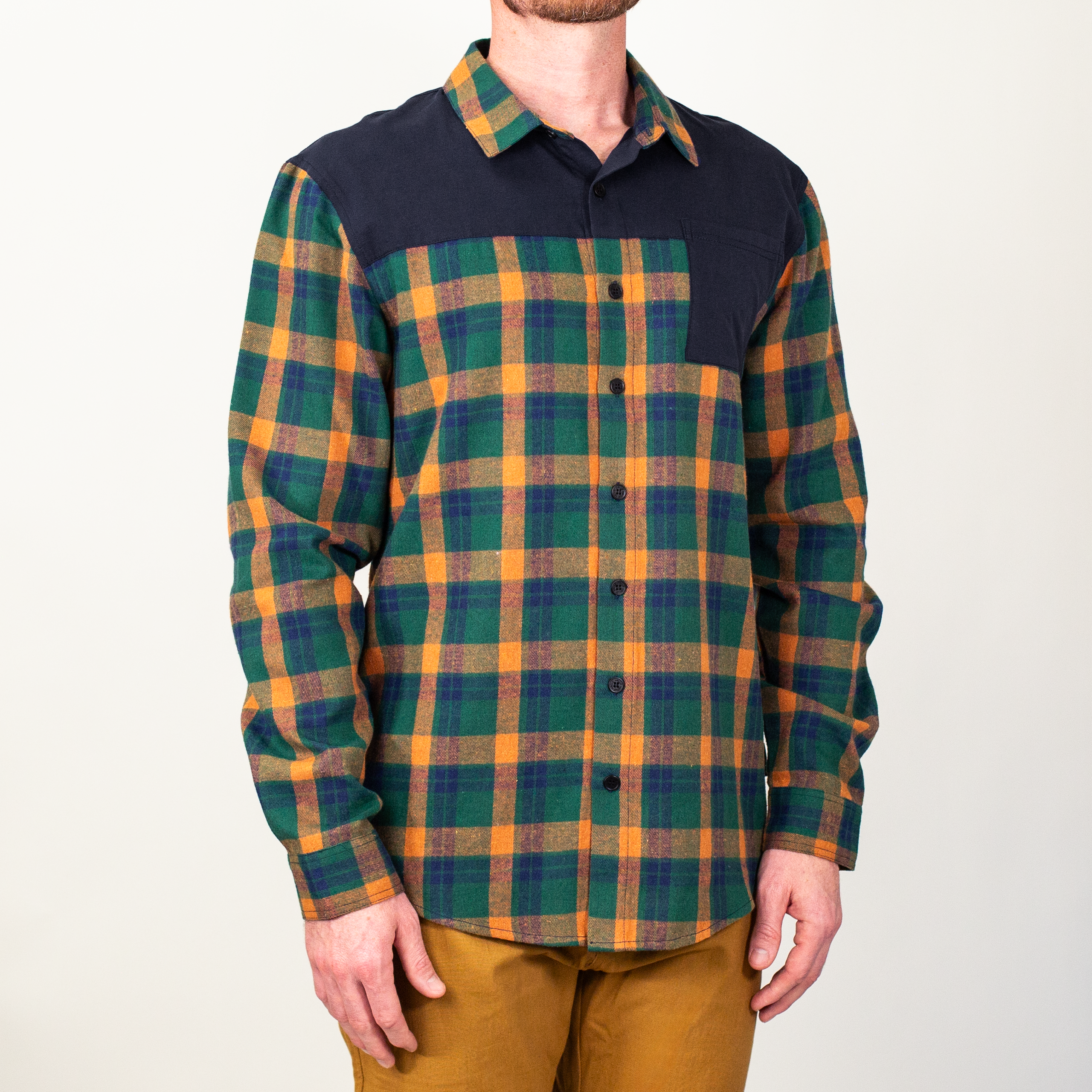 Person wearing a green and orange plaid shirt with a black patch on a white background