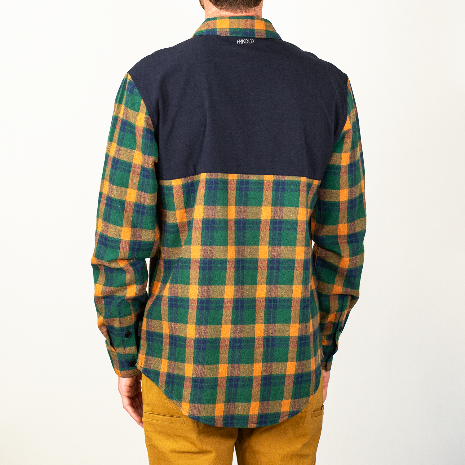 Person wearing a plaid shirt with navy blue and multicolor pattern on a white background