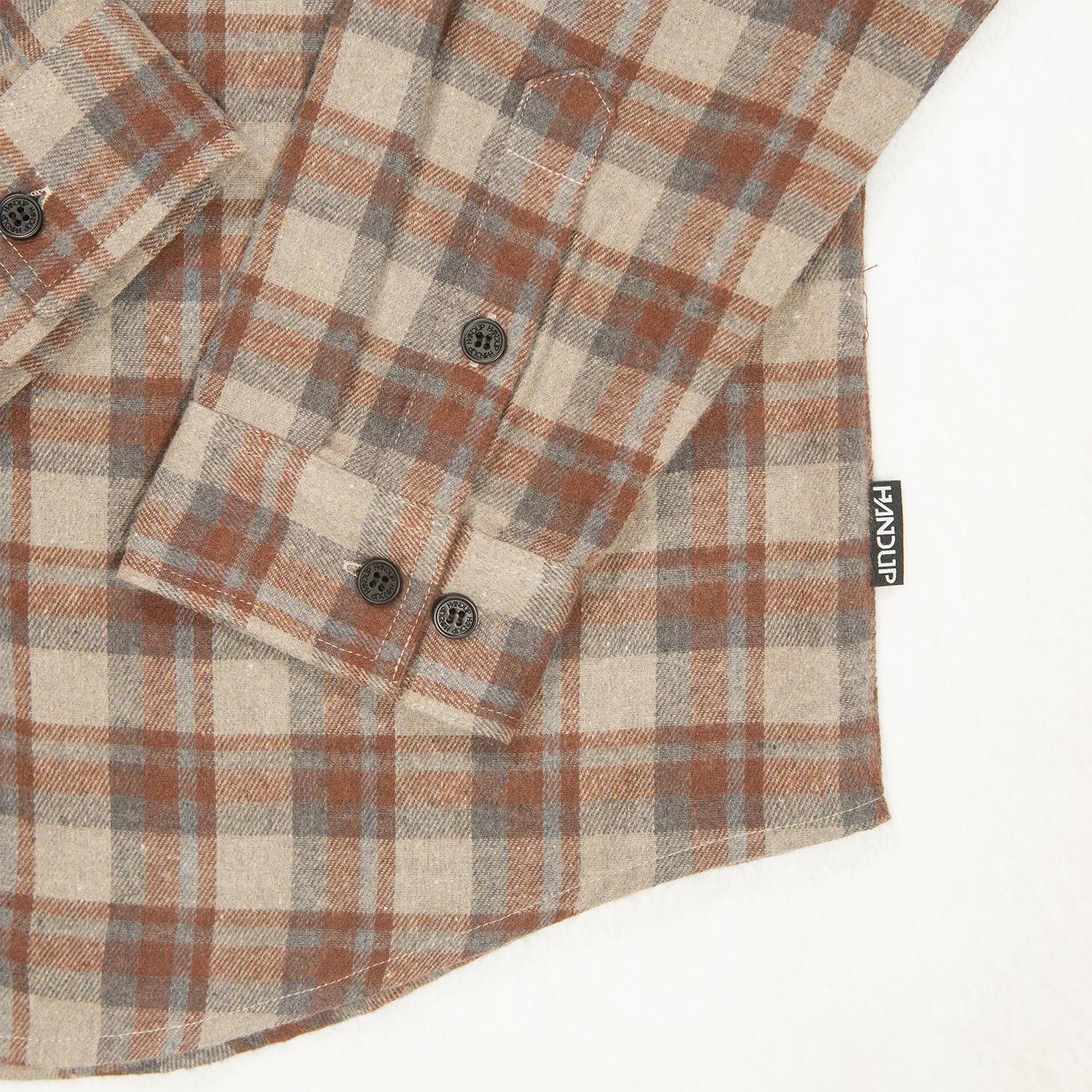 Plaid shirt with buttons and a brand label on a white background