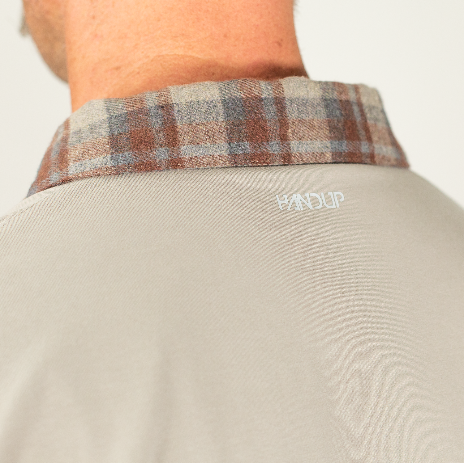 Close-up of a shirt with plaid collar and 'Handup' logo on a plain background