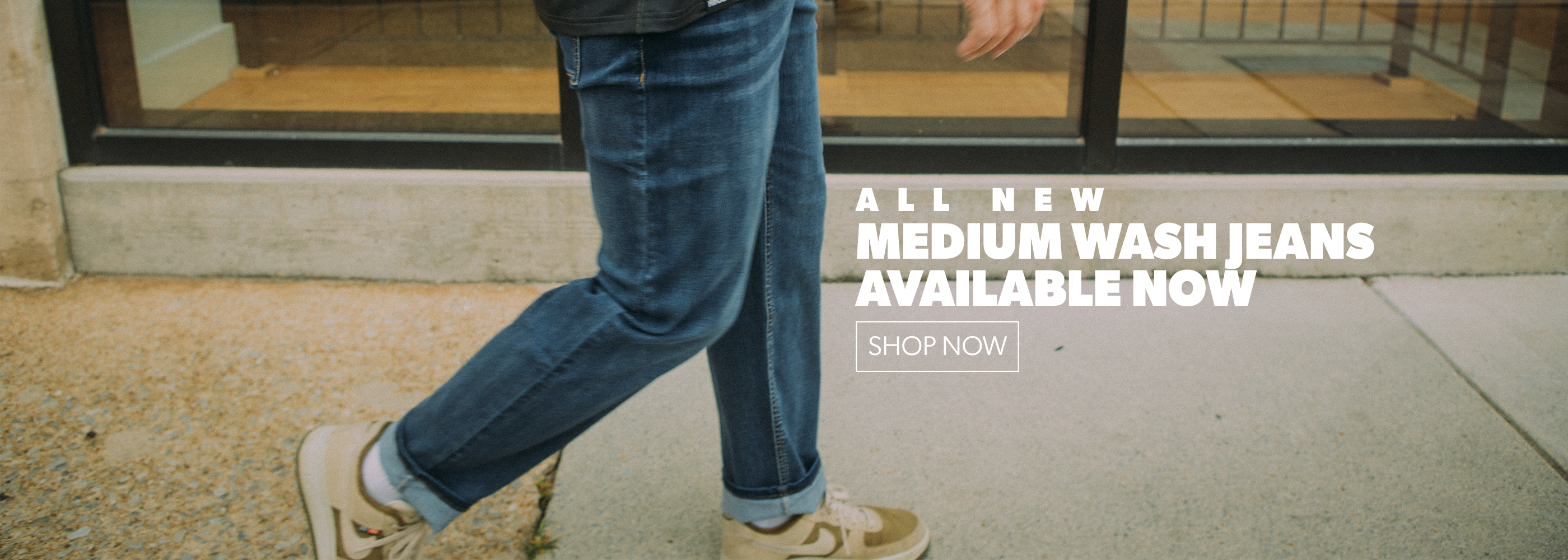 Person wearing blue jeans and white sneakers walking on a sidewalk with text about medium wash jeans.
