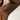 Close-up of a person wearing a brown athletic long-sleeve top with orange curved stripe accents and perforated ventilation holes on the upper arm.
