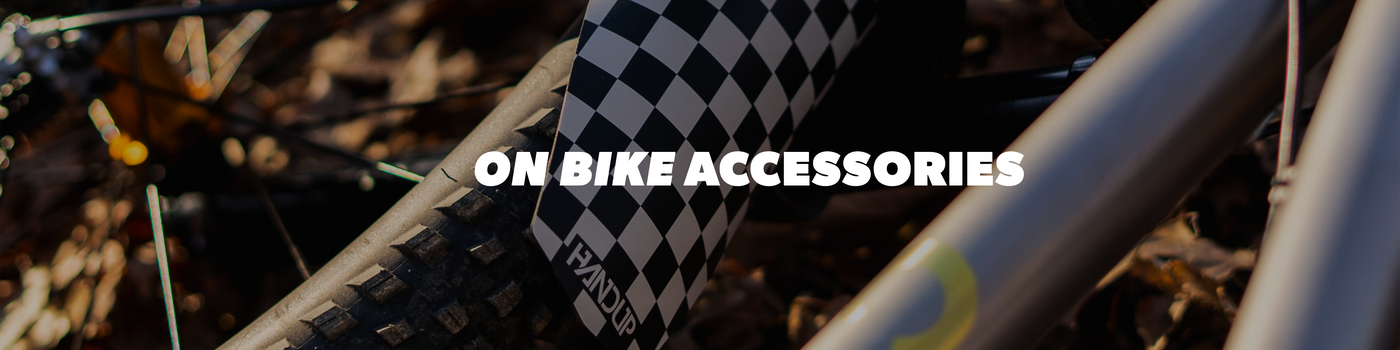 Close-up of a bike tire with checkered pattern and text 'On Bike Accessories' on a blurred natural background.