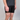 Person wearing black shorts with a visible brand logo on a plain background
