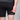 Person wearing black shorts with a visible brand logo on a gray background