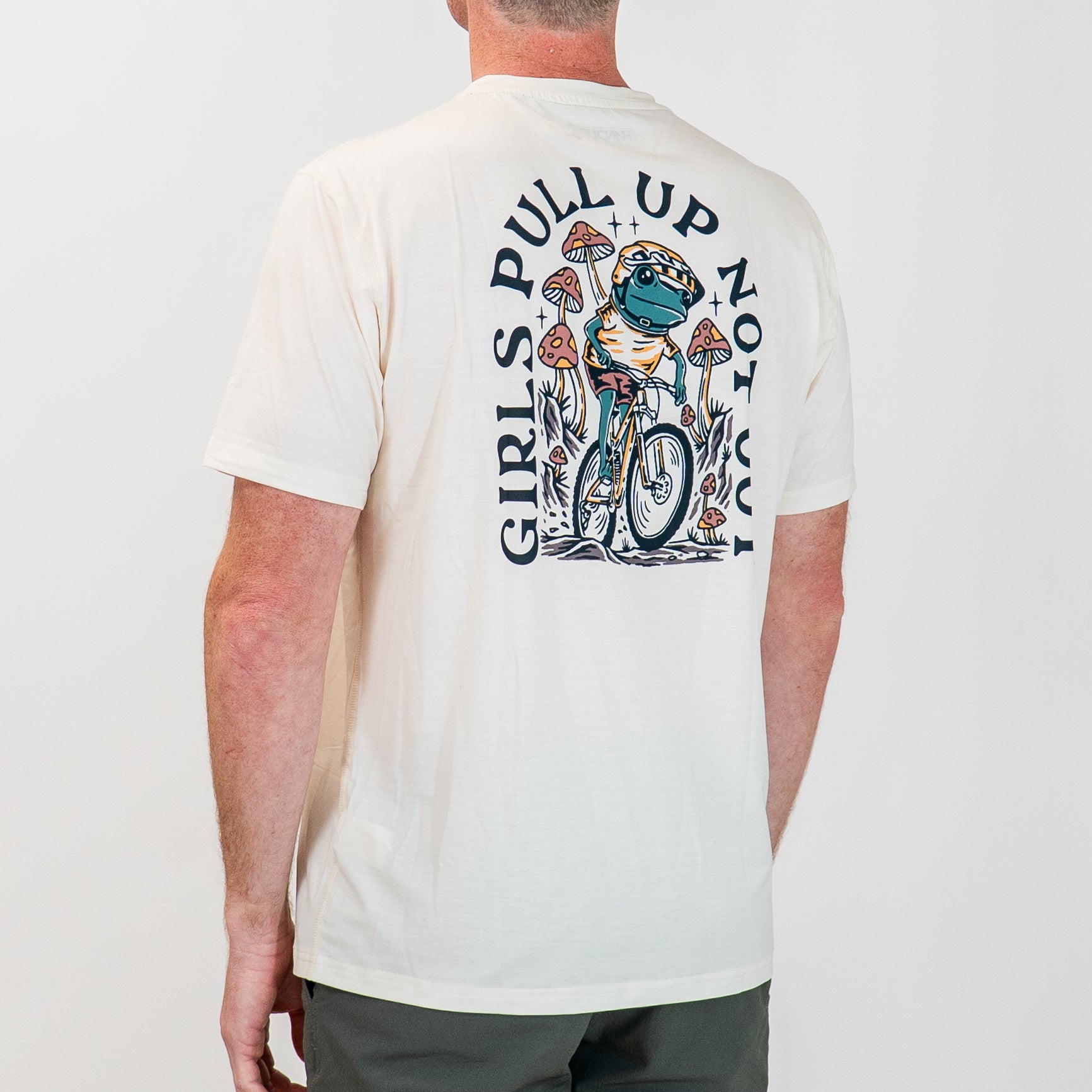 Person wearing an off-white t-shirt with a graphic design of a frog riding a bike