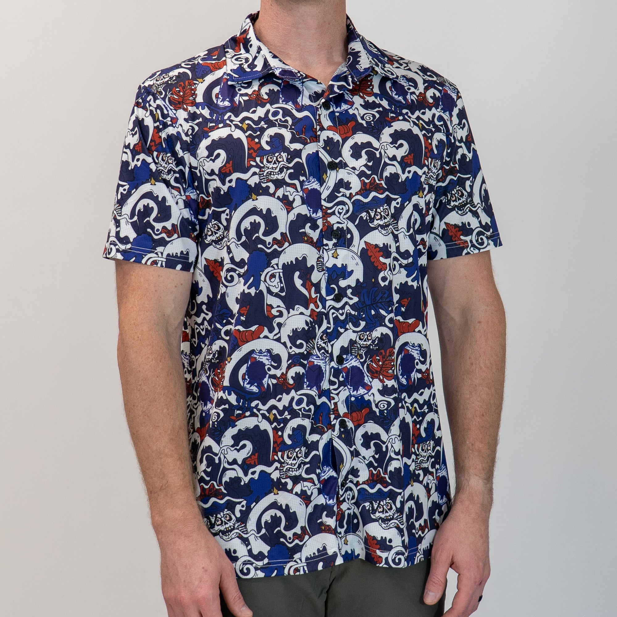 Person wearing a patterned shirt with blue, white, and red design on a plain background