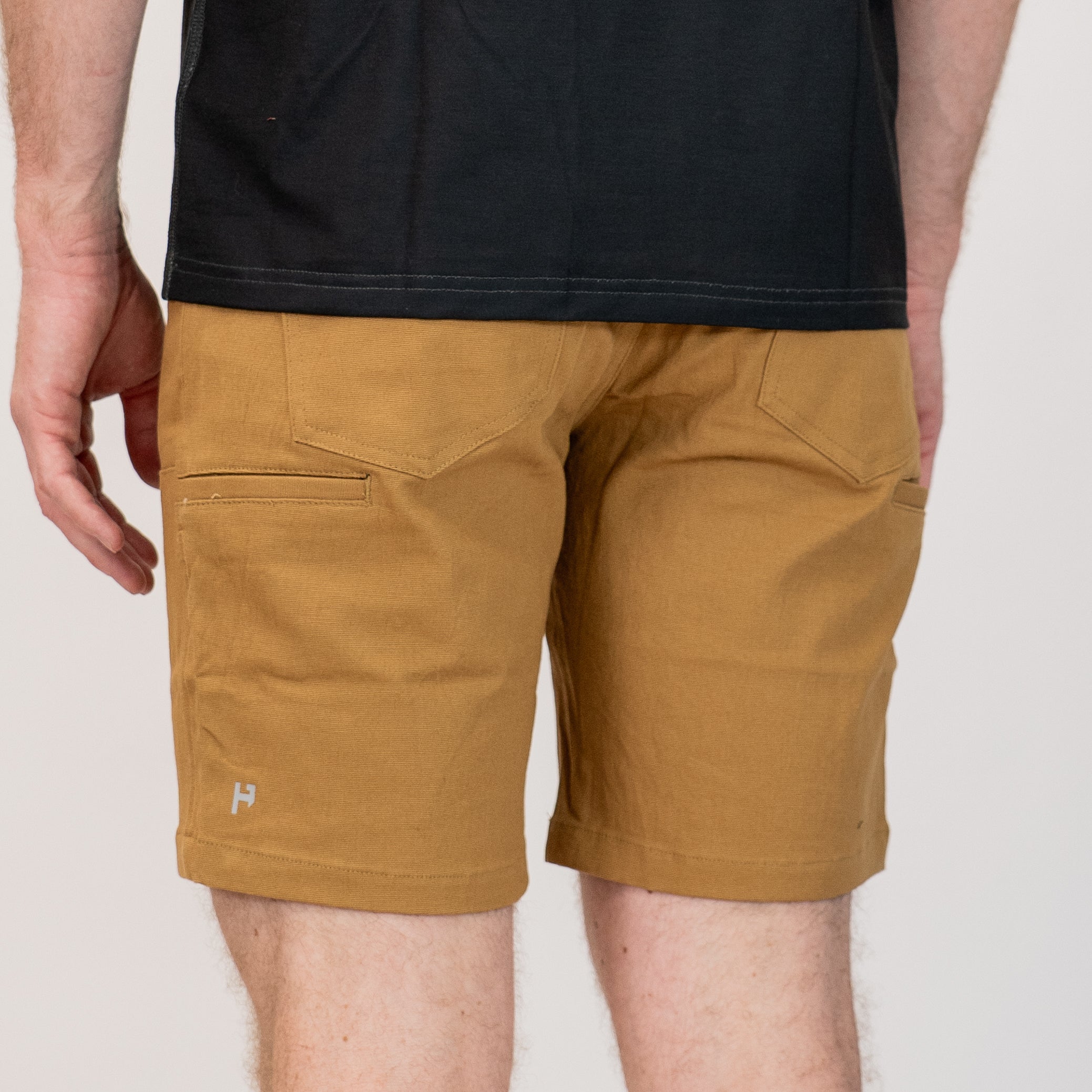 Person wearing brown shorts and a black shirt on a plain background