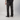 A person shown from the back wearing dark black and brown marbled patterned pants, a black t-shirt, and black Vans sneakers against a light gray studio background.