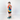 A young boy standing in profile wearing a vibrant rainbow spiral tie-dye t-shirt, black athletic shorts, and teal sneakers against a plain white studio background.