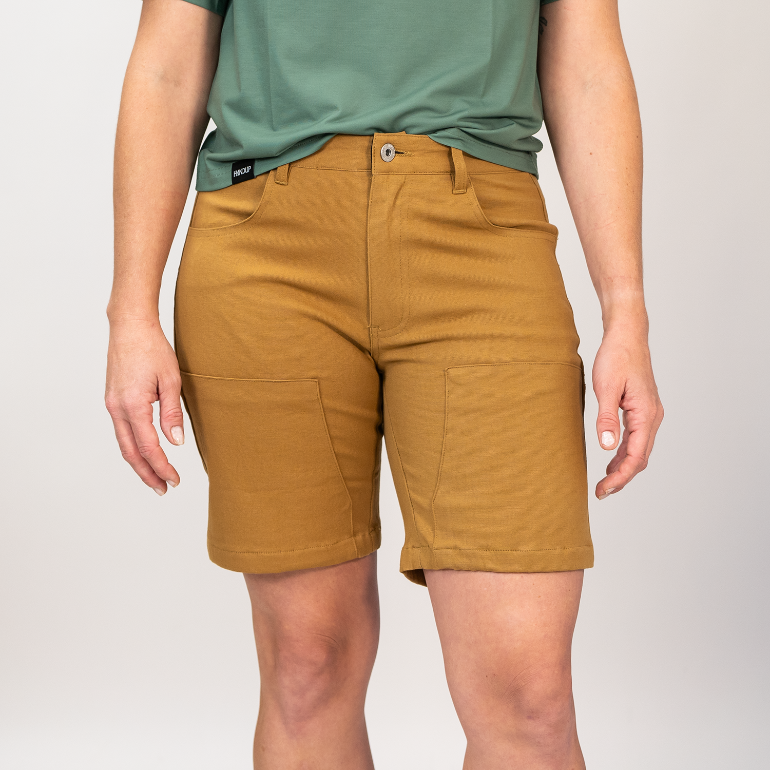 Person wearing brown shorts and a green shirt on a plain background