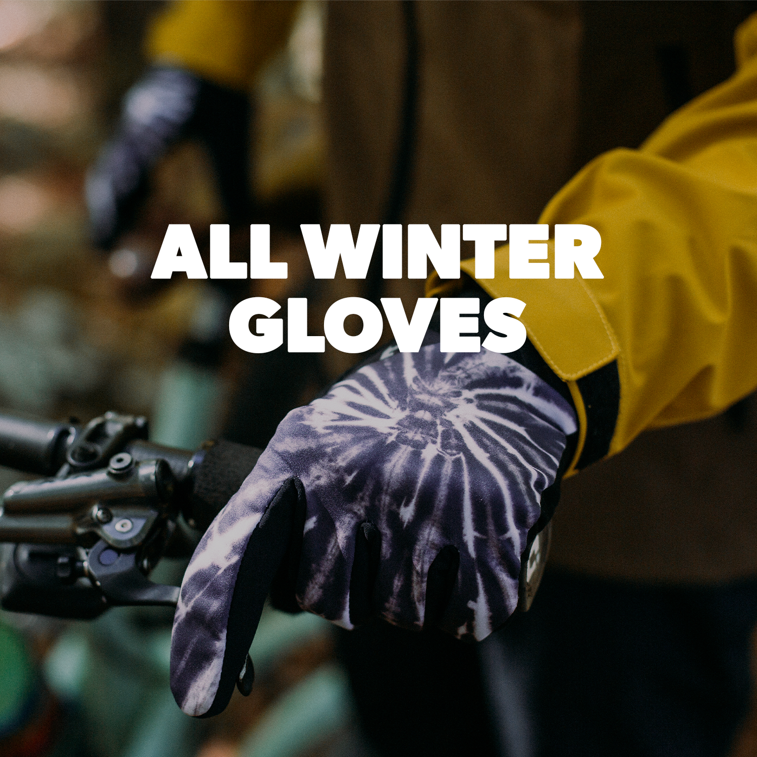close up of someone holding a bike handlebar wearing black and white tie dye gloves with a yellow sleeve