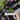 A mountain biker riding through a blurred forest with the text 'VENTOP JERSEY' overlaid on the left side. The rider is wearing a black jersey with pink, blue, and white stripes, gray shorts, and gloves.