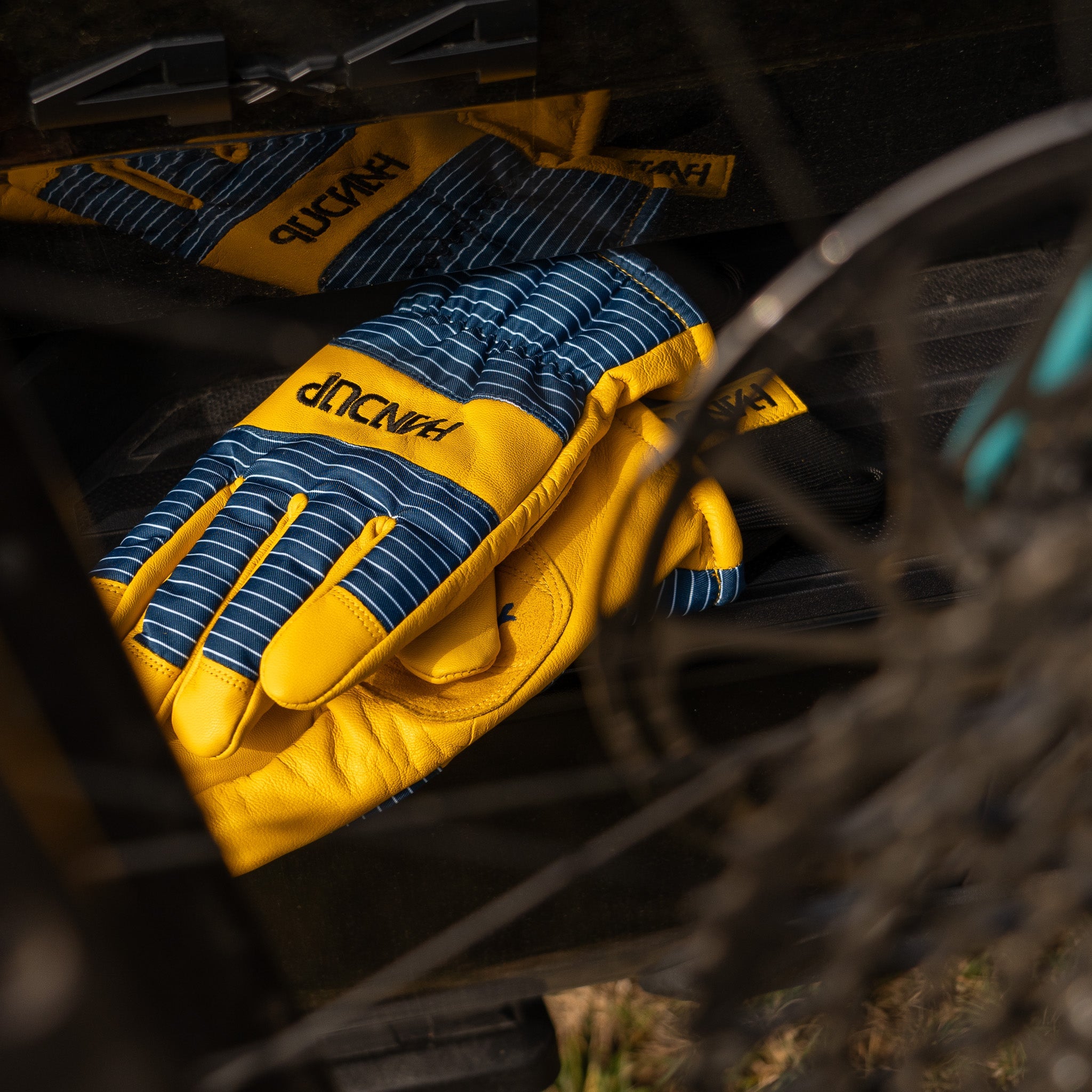 a pair of work gloves with yellow leather and blue striped detail