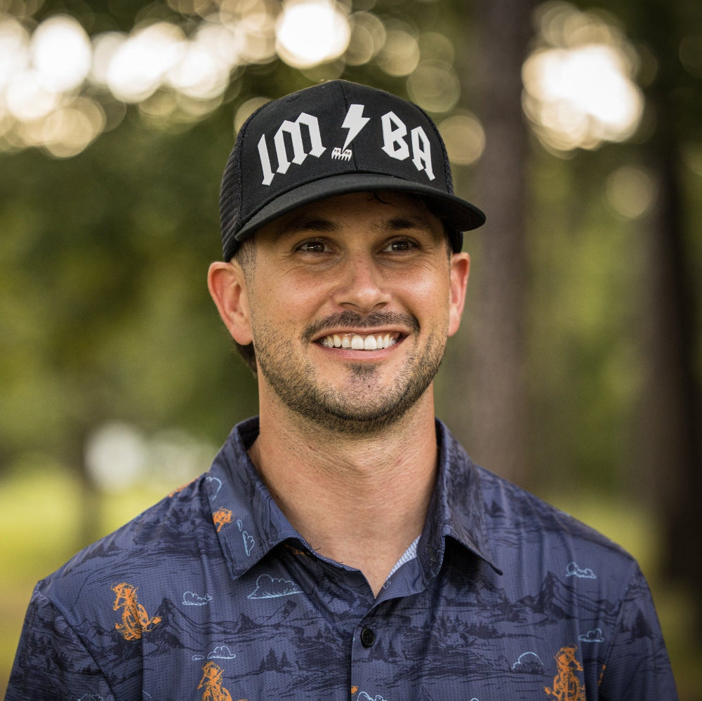 Man wearing a black cap with 'IMBA' logo outdoors