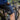 Person on a mountain bike with 'Create Endure Protect' shorts, blurred background of another cyclist.
