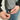 Person adjusting a gray jacket with black strings on a neutral background