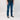Person wearing blue jeans and black sneakers on a white background