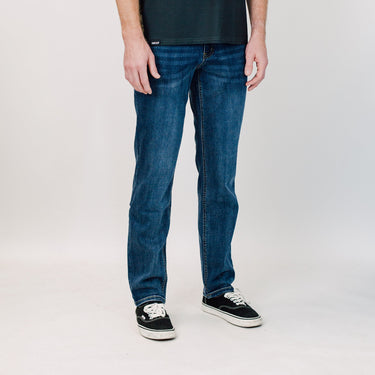 Person wearing blue jeans and black sneakers on a white background