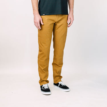 Person wearing mustard yellow pants and black sneakers on a white background