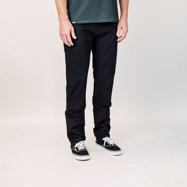 Person wearing black pants and black sneakers on a plain background