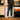 Person standing in a coffee shop with a refrigerator and counter in the background