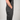 A side profile view of a person wearing dark gray work overalls, showing the side pocket with a zip closure and the brand name 'KNUCK' on a small black label.