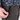 Close-up of a person's hand opening a zippered pocket on dark brown pants, with a patterned shirt featuring dinosaurs and space-themed illustrations visible at the waist. A small 'HANDUP' brand tag is visible on the shirt.