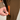 Close-up of a person's hand opening a bright orange zippered pocket on brown pants.
