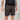 Person wearing dark shorts and a black shirt on a plain background