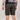 Person wearing black shorts on a plain background