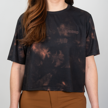 Person wearing a black tie-dye t-shirt with 'Handup' branding on a plain background