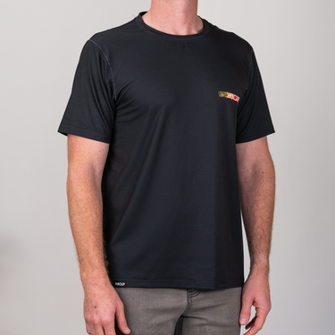Person wearing a black t-shirt with a small logo on a plain background