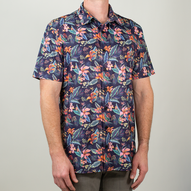 Person wearing a colorful floral patterned shirt on a plain background