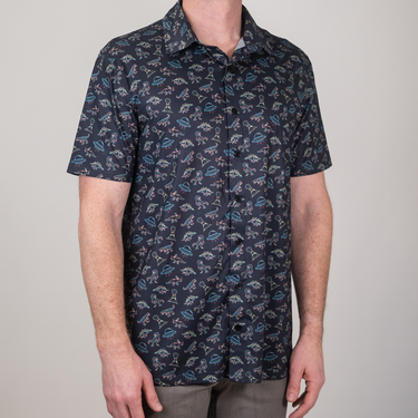 Person wearing a navy blue short-sleeve shirt with a pattern on a plain background