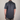Man wearing a navy blue patterned shirt on a plain background