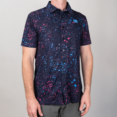 Person wearing a short-sleeve shirt with a colorful abstract pattern on a plain background