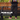 A person standing outdoors in front of a wooden bench and green grass, wearing dark work pants with white paint splatters and a black graphic T-shirt. Large text reads 'WORK HORSE STRETCH CANVAS' with a 'SHOP NOW' button below.