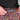 Close-up of a person wearing colorful patterned swim trunks and a black shirt, adjusting the turquoise drawstring of the shorts.