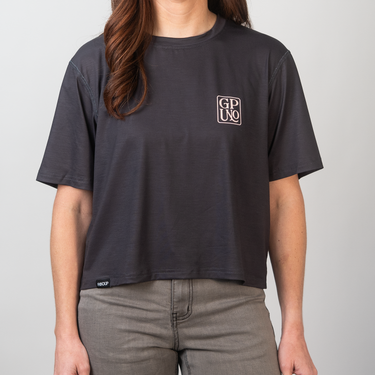Person wearing a black t-shirt with a logo on a plain background