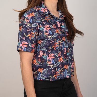 Person wearing a colorful floral patterned shirt against a plain background