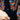Close-up of a person wearing a black shirt with colorful patterned sleeves and cuffs.