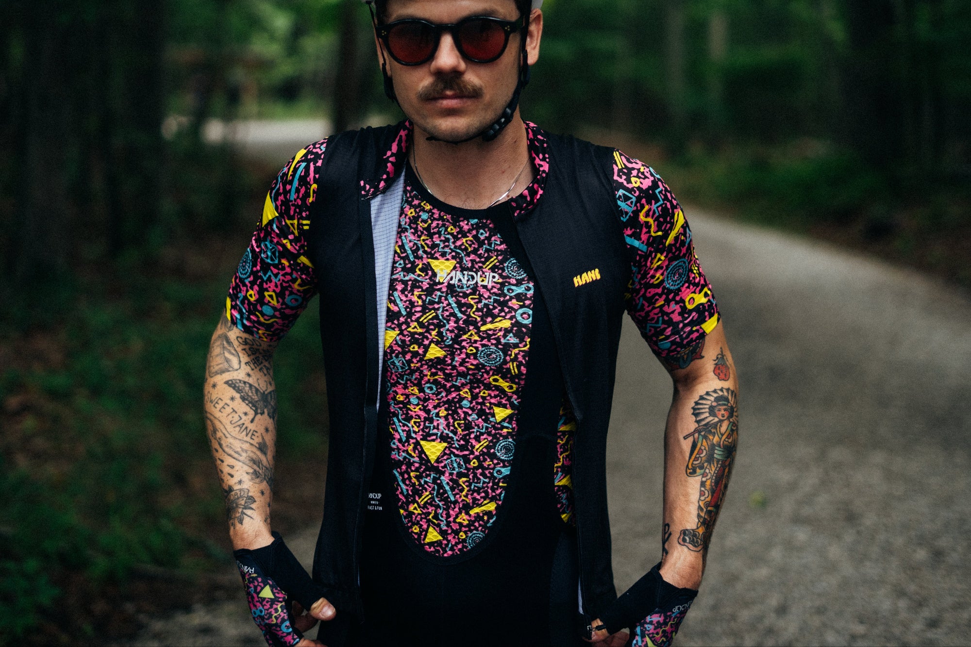 Man wearing a colorful outfit with a helmet and sunglasses on a forest path