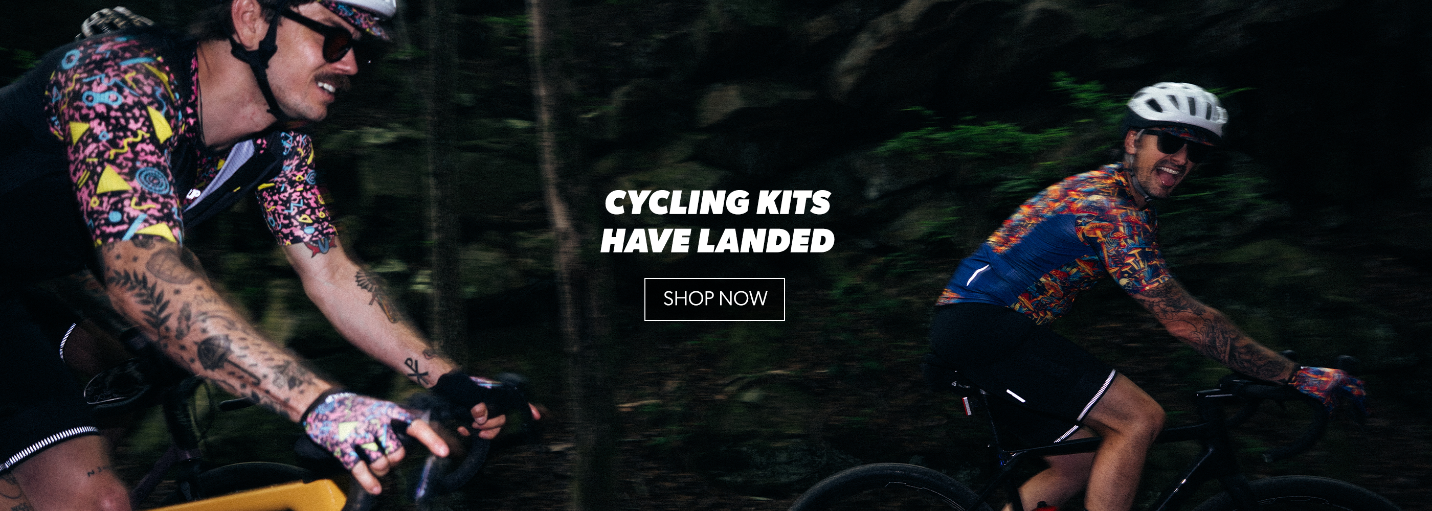 Two cyclists on a forest trail with text overlay 'Cycling Kits Have Landed' and 'Shop Now'.